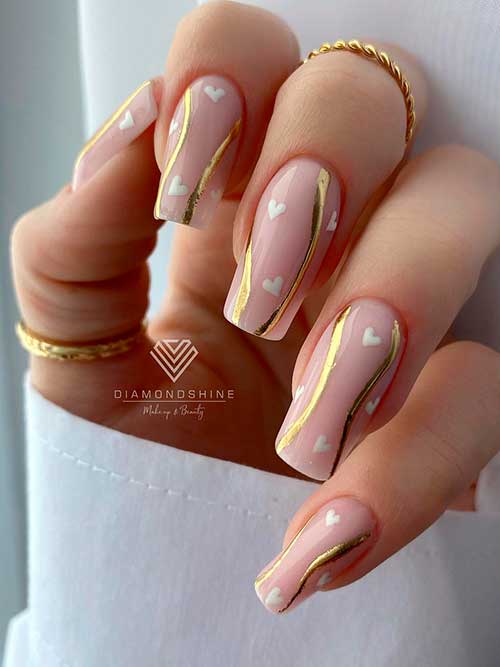 Long square shaped nude valentines nails with gold swirls and white hearts are one of the cutest valentine nail designs