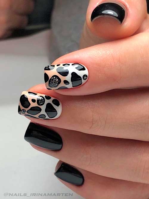 Short Square Shaped Black Nails with Cow Print on Two Accent Nails Adorned with Silver Glitter