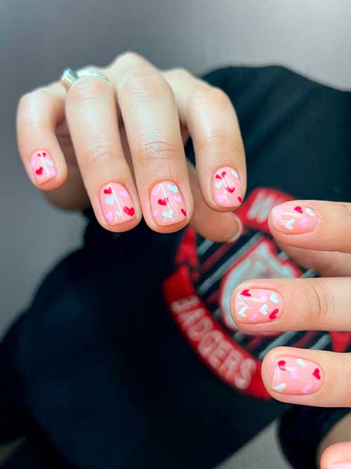 Short nude pink nails with red, pink, and white hearts are one of the best valentine nail designs 2023