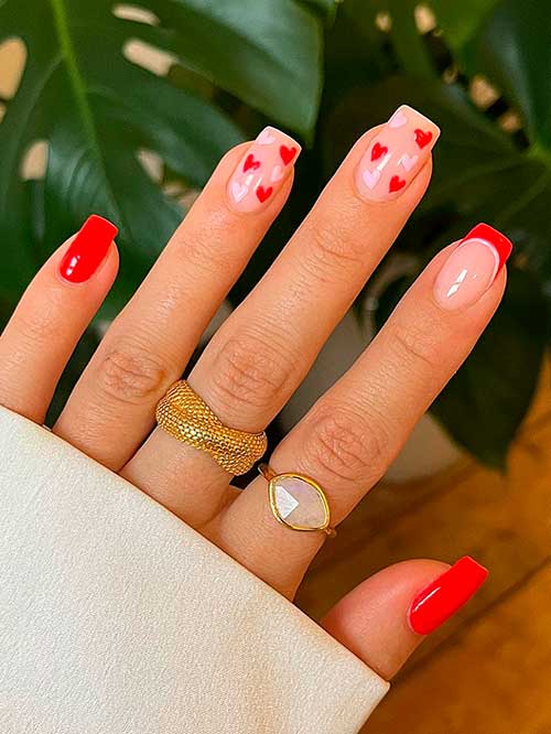 Short Red Valentine’s Day Nails Short red valentines nails 2023 with pink and red heart shapes on two accent nails besides a French tip accent nail
