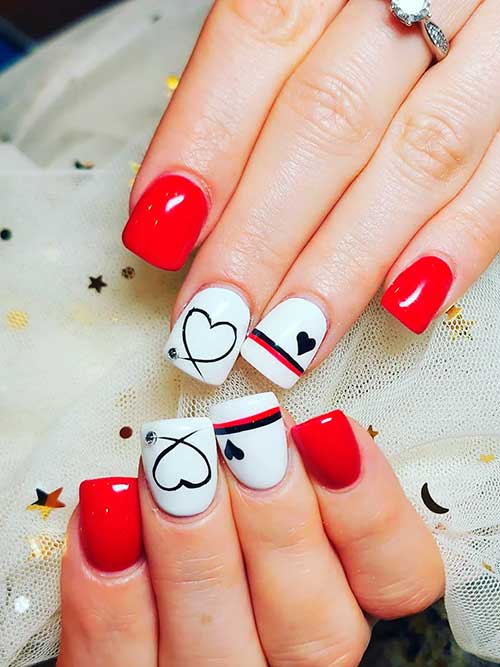 Short square shaped red and white valentine’s nails with black heart shapes to celebrate Valentine’s Day 2023