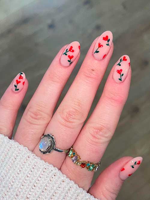 Short almond-shaped nude spring nails with red flowers are one of the perfect spring nail ideas for 2023