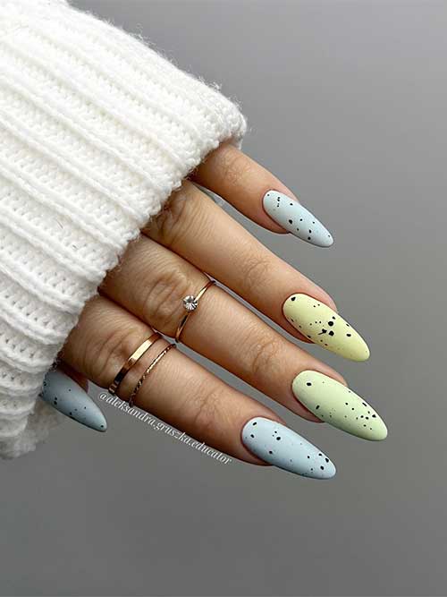 Long almond-shaped matte pastel blue and green nails with black speckles