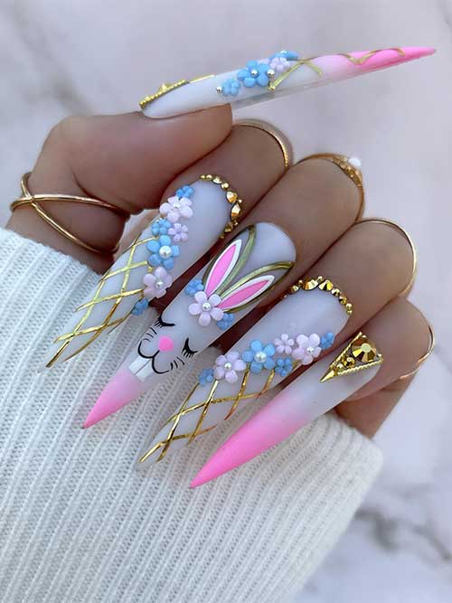 Long stiletto white pink ombre Easter nails with gold rhinestones, flowers, and a bunny shape