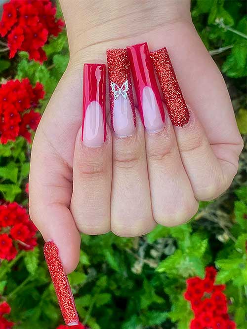 long red French nails with glitter and a butterfly rhinestone