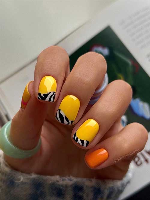 Short square-shaped bright yellow nails with twisted zebra print French tips and orange accent nails