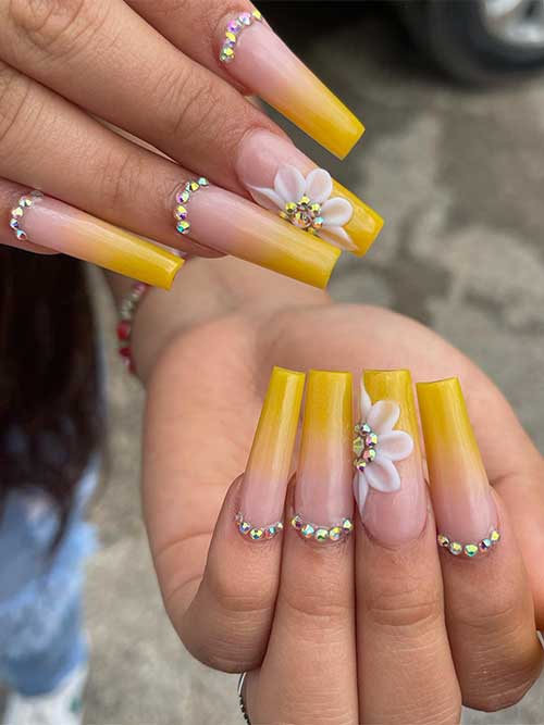 Long square-shaped ombre yellow acrylic nails with silver rhinestones and 3d a white flower