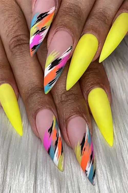 Long stiletto neon yellow acrylic nails with multicolored abstract nail art on two accent nude nails