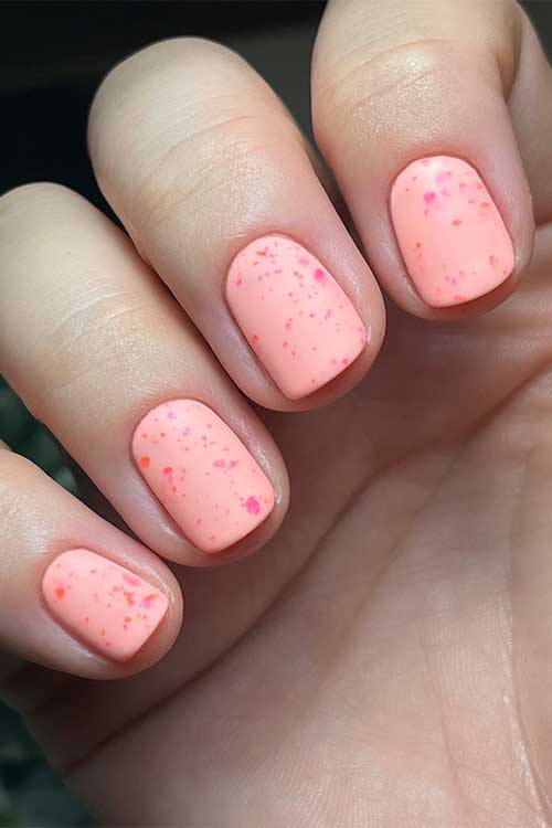 Matte peach short summer nails with neon pink and orange splatters