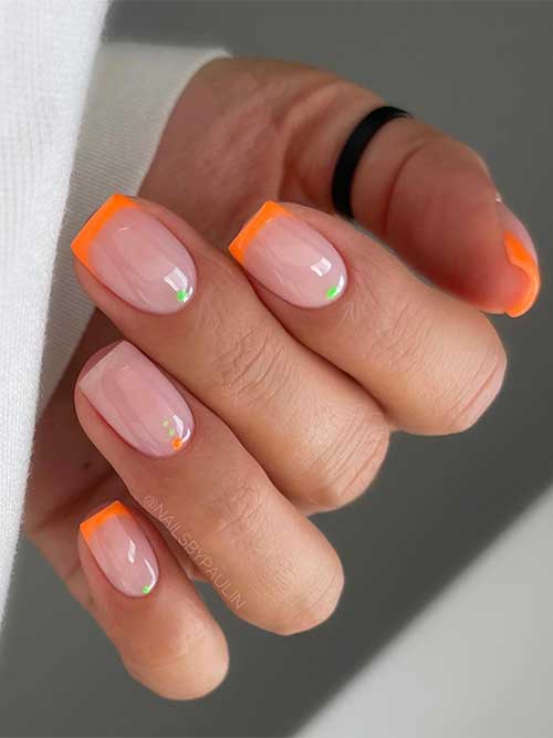 Short neon orange summer French tip nails with a green dot on the nail base