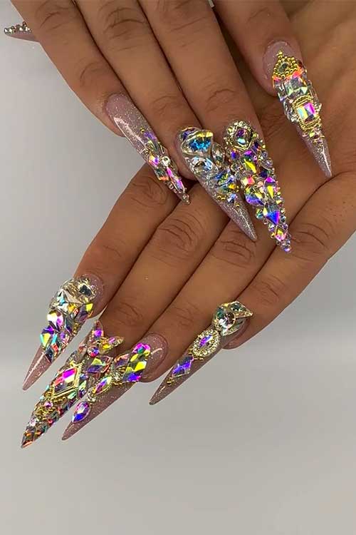 Long nude stiletto nails with glitter and sparkle crystal rhinestones that create multicolored reflections