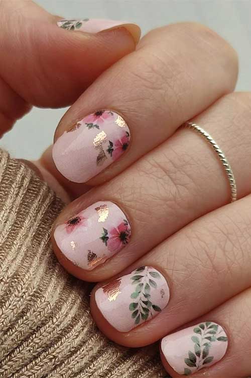 Short fairy nails feature nude pink base color with pink flowers and green leaves and some gold foil patches