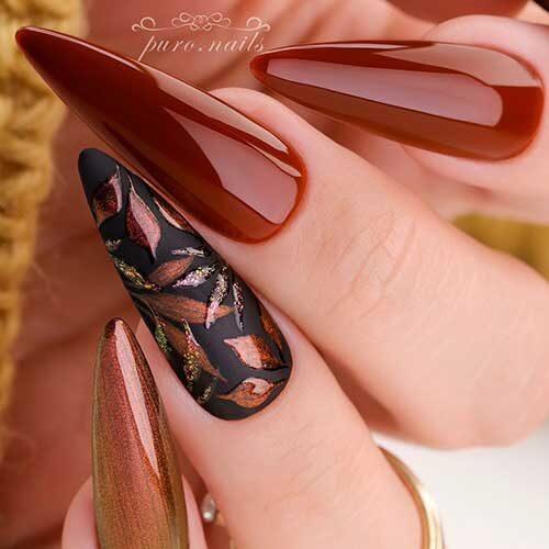 Chestnut and black nails with chestnut leaves on an accent nail are one of the best September nail ideas to try
