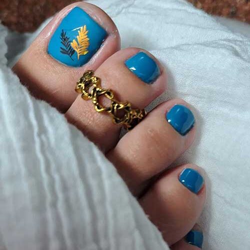 Denim blue toe nails with black and burnt yellow leaves on the big toe nail is one of the perfect fall toe nail designs