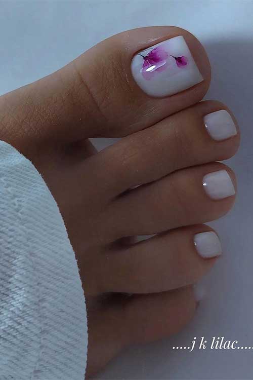 Elegant white toe nails with pink purple flowers on the big toe nail.
