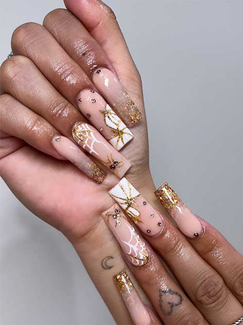 Halloween nude nails with gold glitter tips and white pumpkins and spider webs adorned with rhinestones. Halloween nude nails with gold glitter tips and white pumpkins and spider webs adorned with rhinestones.