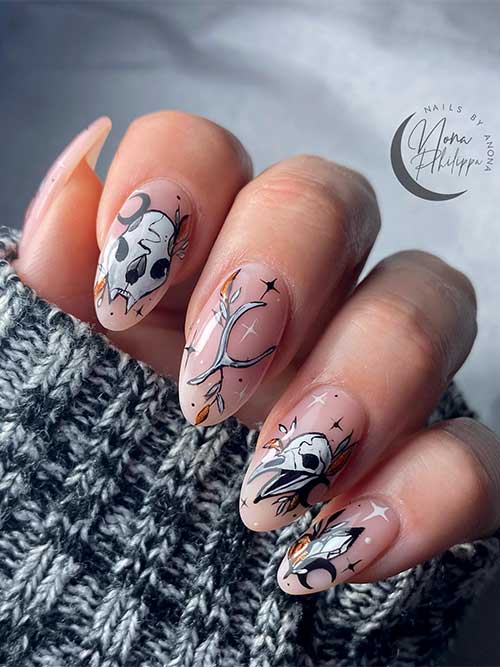Halloween witchy nails with white and black celestial, bones, and skulls nail art over nude base color.