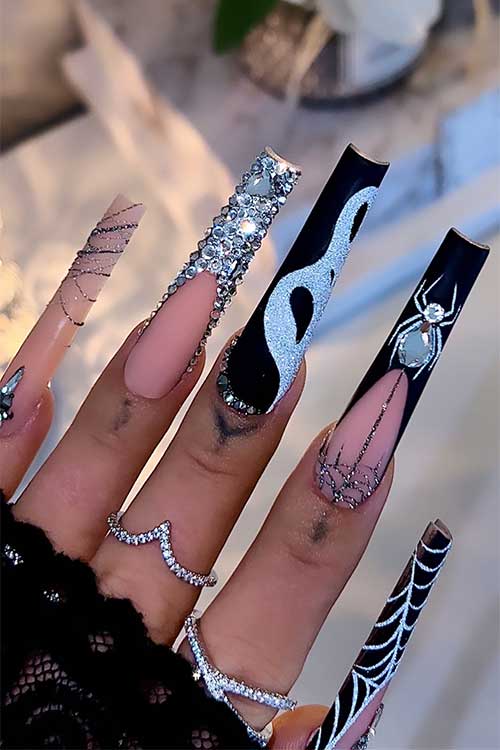 Long Black French tip nails with cobweb nail art, scary face nail art, and adorned with silver glitter and rhinestones