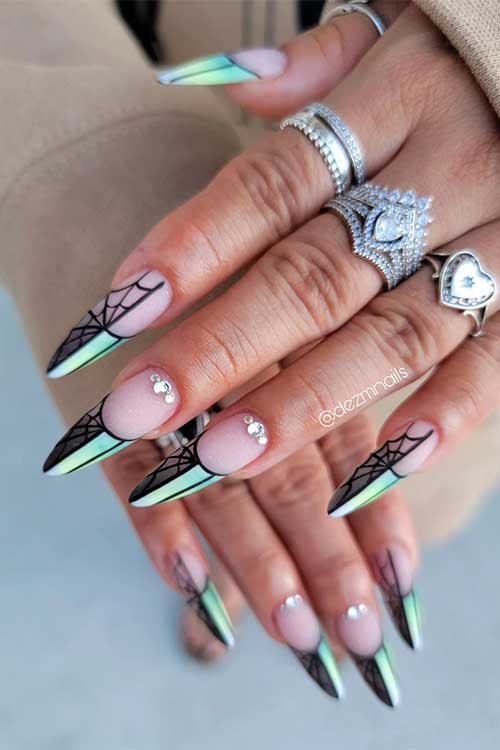 Long almond-shaped matte French Halloween nails feature half black cobwebs half green tips. Long almond-shaped matte French Halloween nails feature half black cobwebs half green tips.