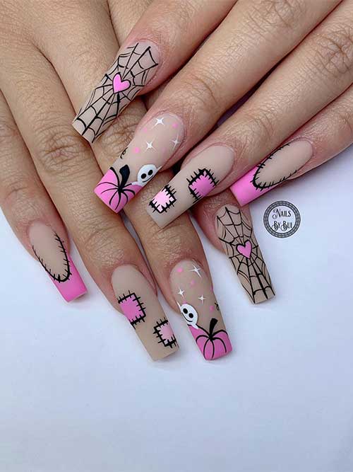 Matte pink and nude Halloween nail art idea features cobweb, pumpkins, ghosts, and stitches nail art