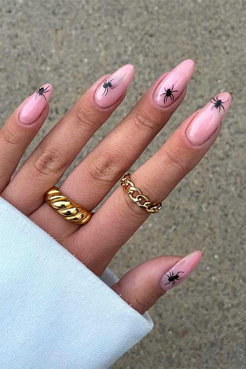 Nude almond shaped nails with a black spider on each nail.