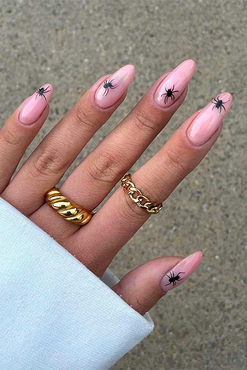 Nude almond shaped nails with a black spider on each nail. Nude almond shaped nails with a black spider on each nail.