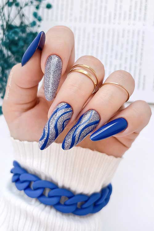 Long almond shaped sparkling Ultramarine Nails with silver glitter and swirl nail art on two accent nails.