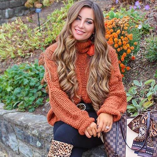 Terracotta sweater and blue pants are incorporated with leopard high boots as fall outfits women for 2023