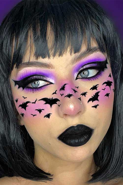 Bat makeup look features light and dark purple eyeshadows, black bat graphic eyeliner, many small black bats, and black lips