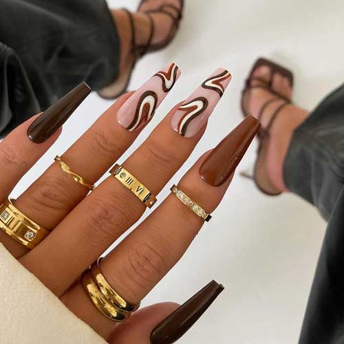 Brown coffin nails with swirl nail art using dark brown, light brown, and white colors on two accent nude nails 