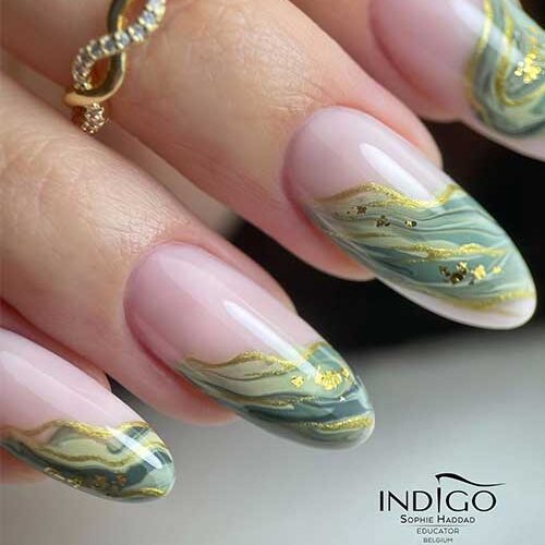 Classy French fall green nails with a twist that uses green marble nail art adorned with gold polish and gold flakes