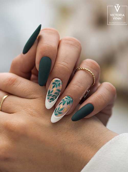 Dark green fall nails with two white French tip nails adorned with green leaf nail art and gold flakes