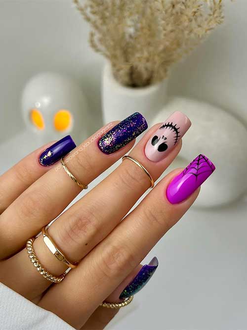 Dark purple Halloween nails with glitter and nude and magenta accent nails feature a cobweb and a scary face Dark purple Halloween nails with glitter and nude and magenta accent nails feature a cobweb and a scary face