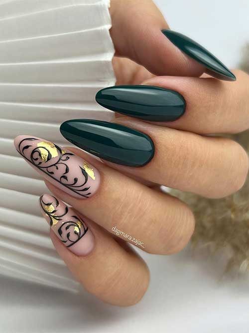 Glossy dark green nails almond-shaped with two matte nude nails adorned with black decorations and gold flakes