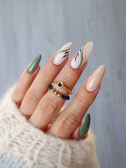 Light fall green nails with an accent beige nail and two milky white nails adorned with swirls and black dots and leaves