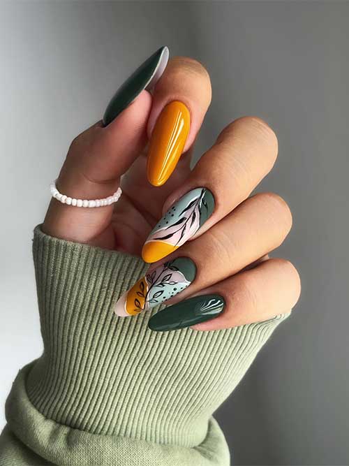 Long almond-shaped burnt yellow with fall green nails with abstract nail art and black leaves on two accent nails