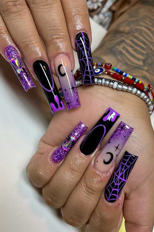 Long black and purple Halloween nails with glitter, rhinestones, celestial nail art, dripping nail art, and cobwebs.