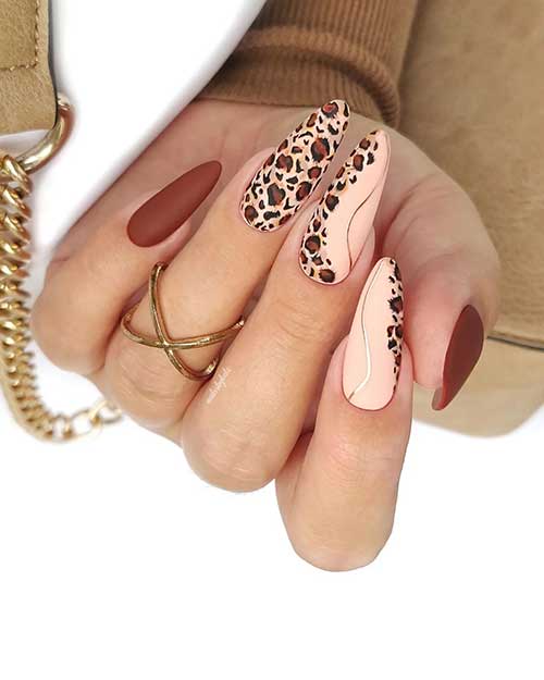 Long light brown nails with black and brown leopard animal print on three matte nude nails adorned with metallic gold swirls