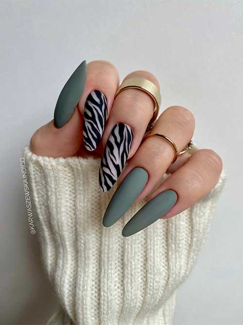 Long matte olive green nails with black zebra animal prints on two accent nude nails