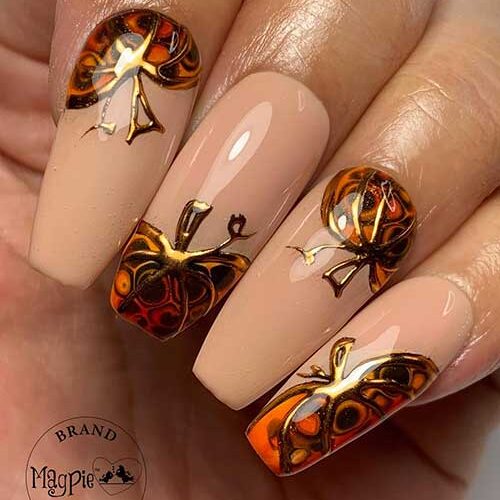 Long nude coffin nails with a pretty pumpkin design on each nail using burnt orange, brown, and gold chrome outlines