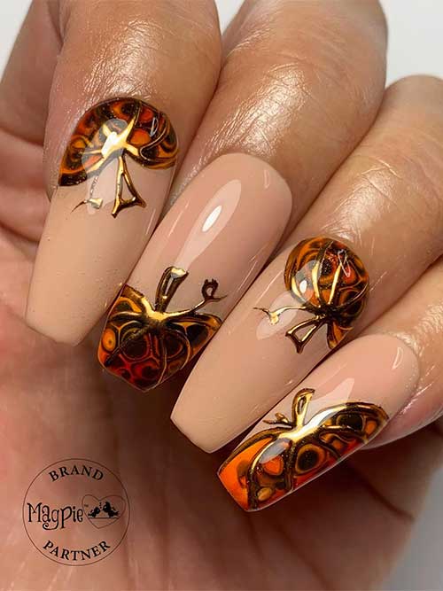 Long nude coffin nails with a pretty pumpkin design on each nail using burnt orange, brown, and gold chrome outlines
