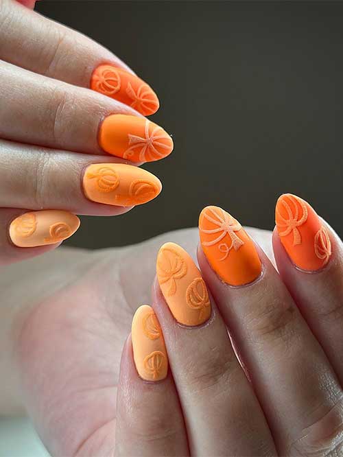 Matte vibrant and pale orange nails with pale orange hand-painted pumpkin outlines with colored gel polish