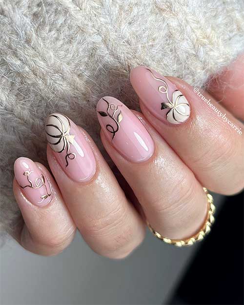Medium almond shaped white pumpkin nails adorned with gold outer lines and gold leaves.