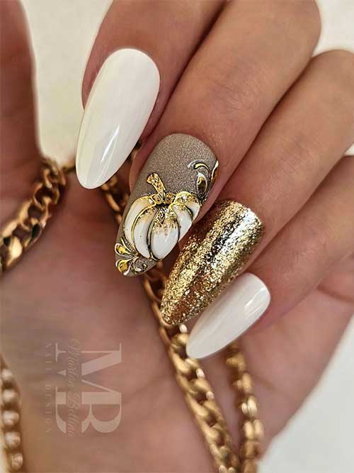 White almond nails with gold glitter accent nail and white and gold pumpkin nail art on another accent nail.