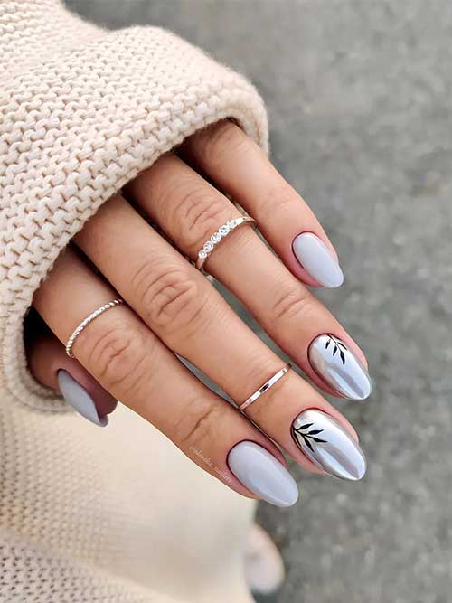 Almond grey nails with two accent silver mirror nails adorned with black leaf nail art.