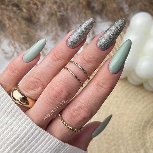 Long almond sage green nails with two accent silver glitter nails.