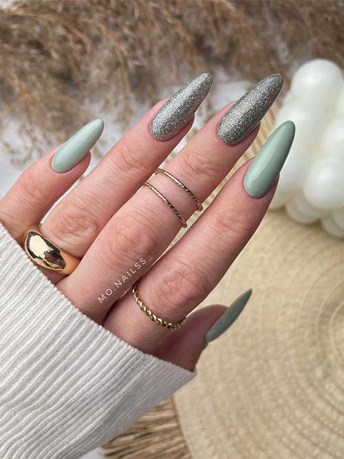 Long almond sage green nails with two accent silver glitter nails.