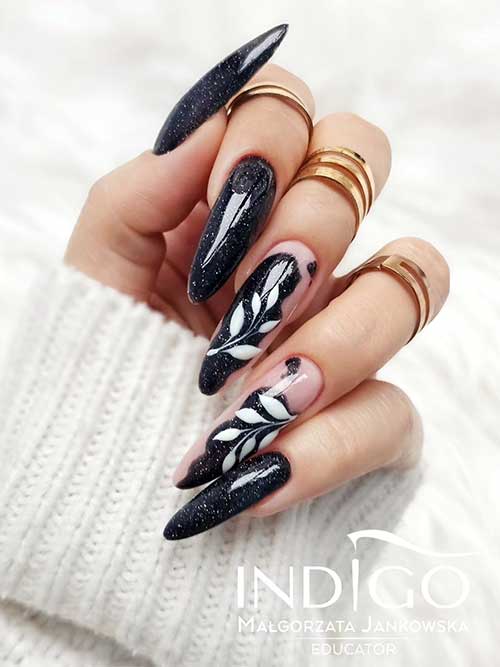 Long almond-shaped glitter black fall nails with white leaf nail art on two accent abstract nails