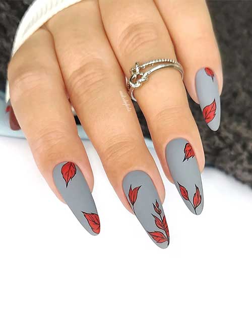 Long almond-shaped matte gray nails with burnt orange fall leaves are perfect November nail ideas