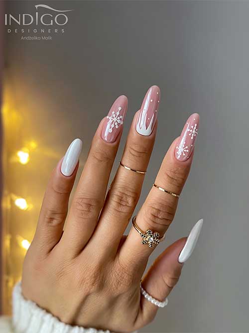 Long almond-shaped white winter nails 2023 with two accent nude nails adorned with white snowflakes and icicle accent nail